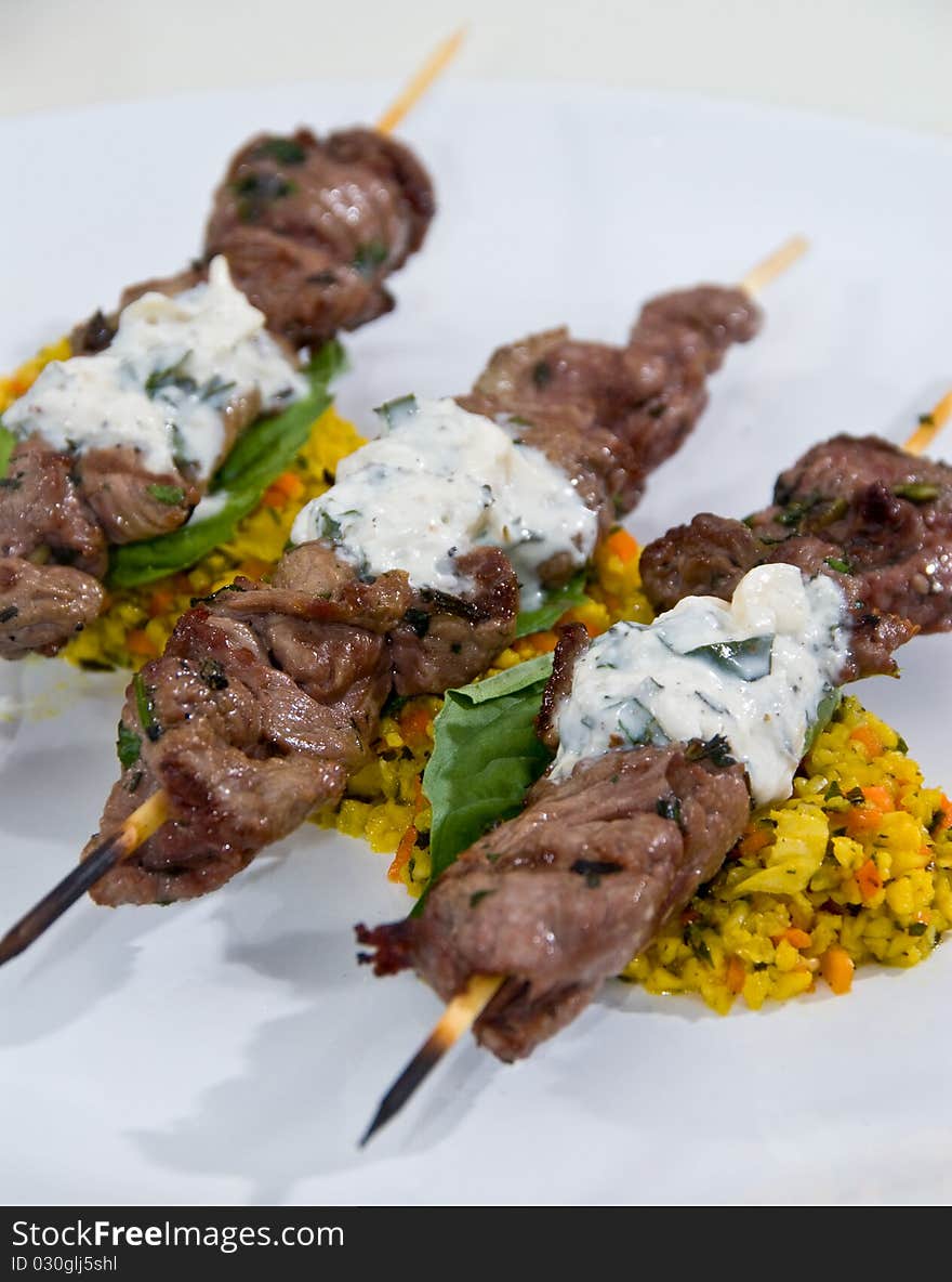 Beef skewers over yellow rice