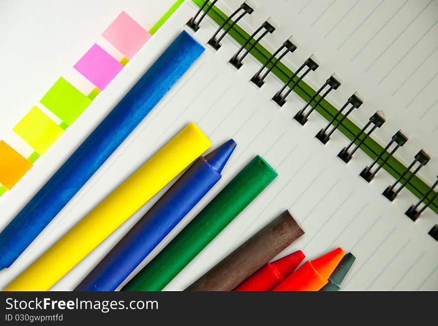 Isolated green notebook on white with colorful crayons. Isolated green notebook on white with colorful crayons