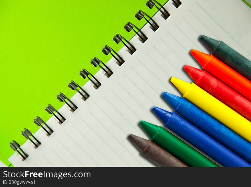 Isolated green notebook on white with colorful crayons. Isolated green notebook on white with colorful crayons