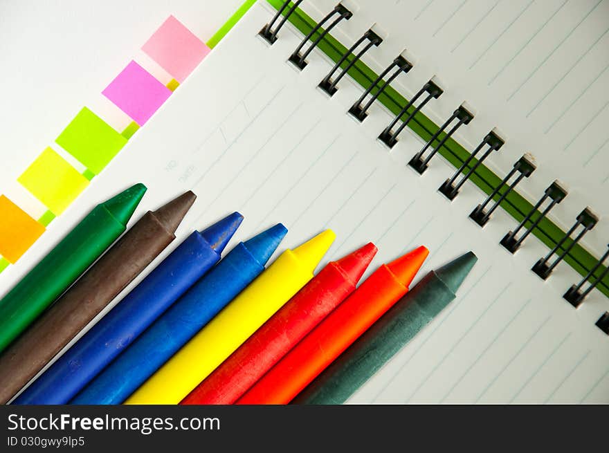 Isolated green notebook on white with colorful crayons. Isolated green notebook on white with colorful crayons