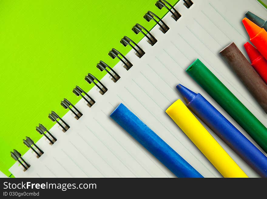 Isolated green notebook on white with colorful crayons. Isolated green notebook on white with colorful crayons