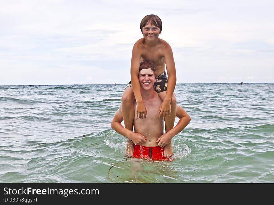 Boys having fun in the beautiful clear sea by playing pickaback