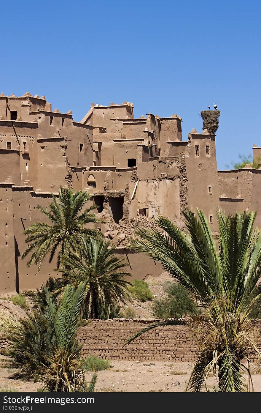 A view of a Moroccan kasbah with some palm trees. A view of a Moroccan kasbah with some palm trees.