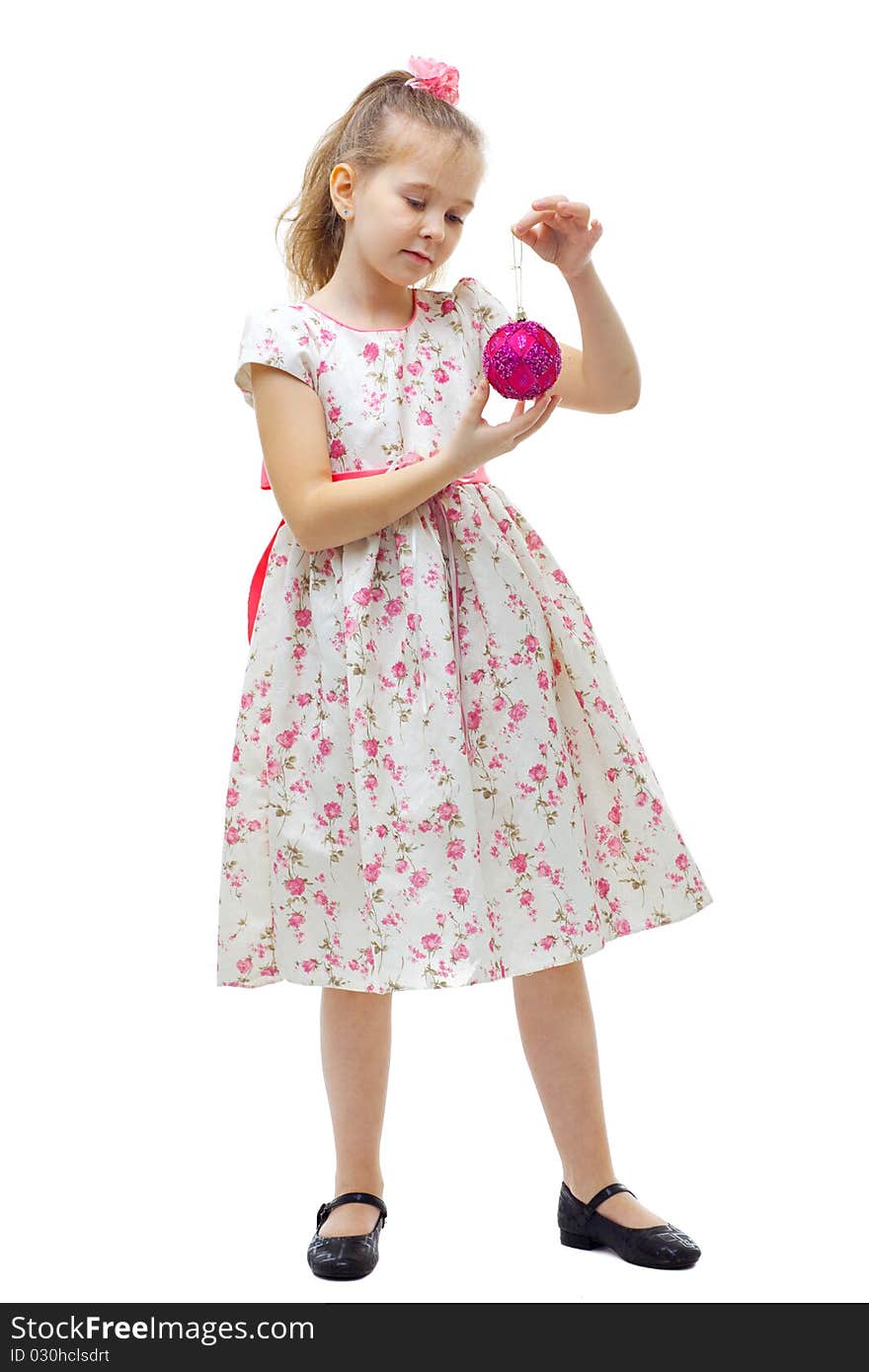 Cute little girl in dress playing with a christmas-tree decoration on white background isolated