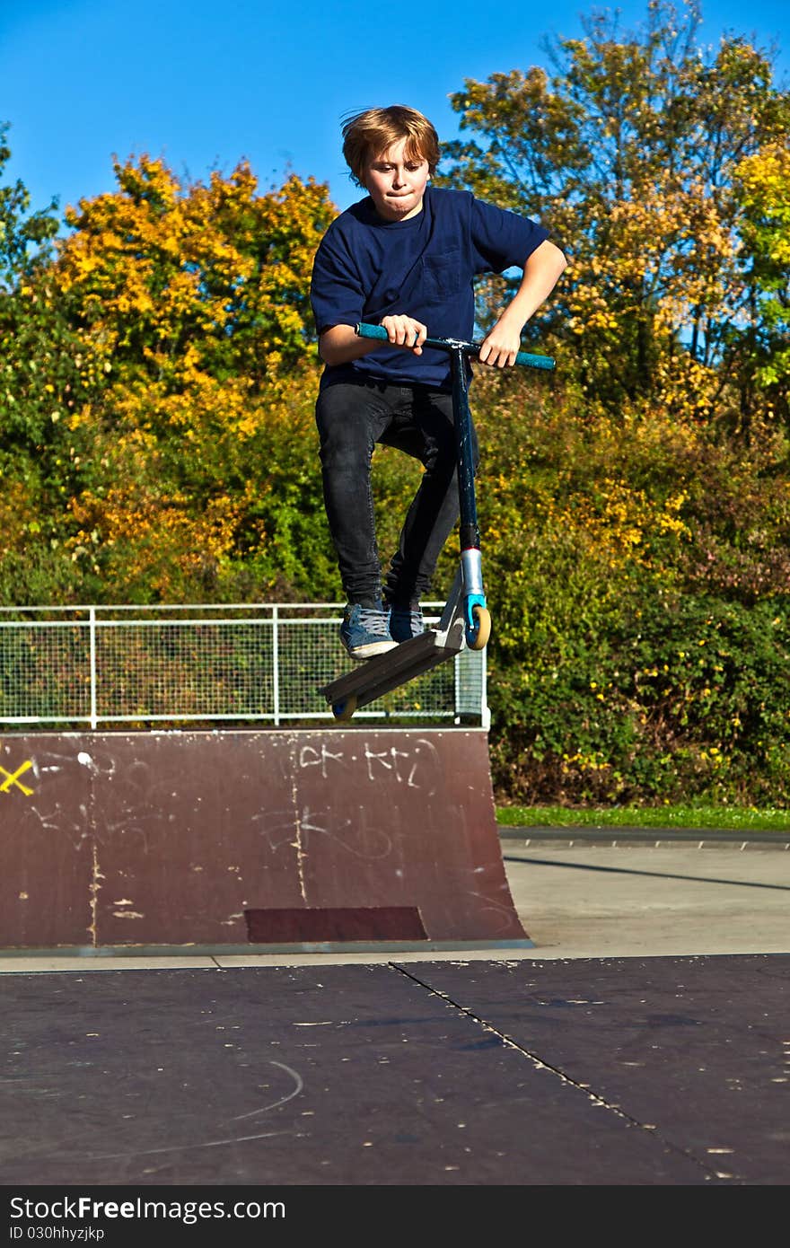 Young boy going airborne with his scooter. Young boy going airborne with his scooter