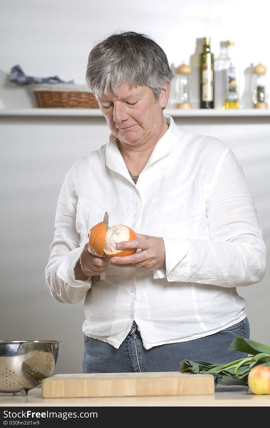 Women is peeling a Orange in the kitchen