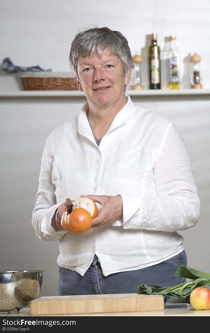 Women is peeling a Orange in the kitchen