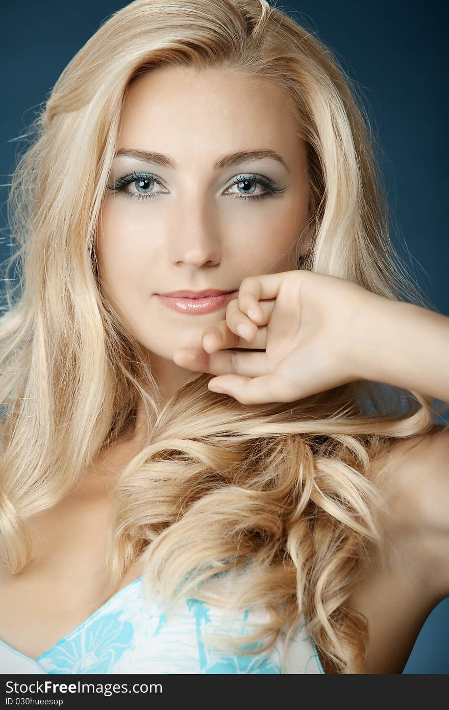 The beautiful girl in a blue dress on a dark blue background