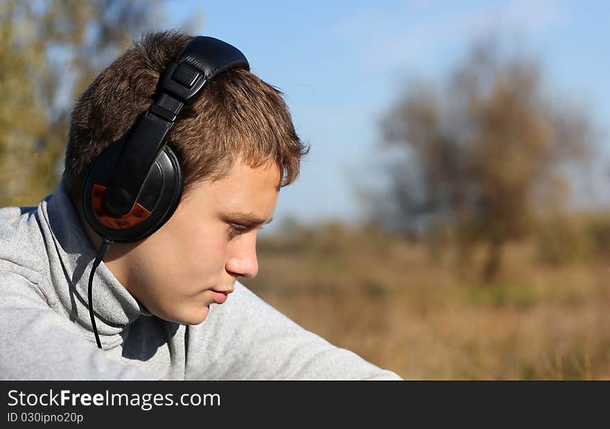 Boy Enjoying Music in headphones in autumn day