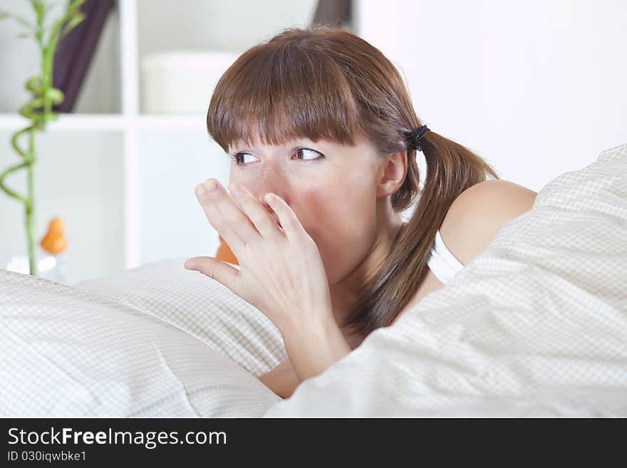 Young woman awaking and yawning in bed. Young woman awaking and yawning in bed