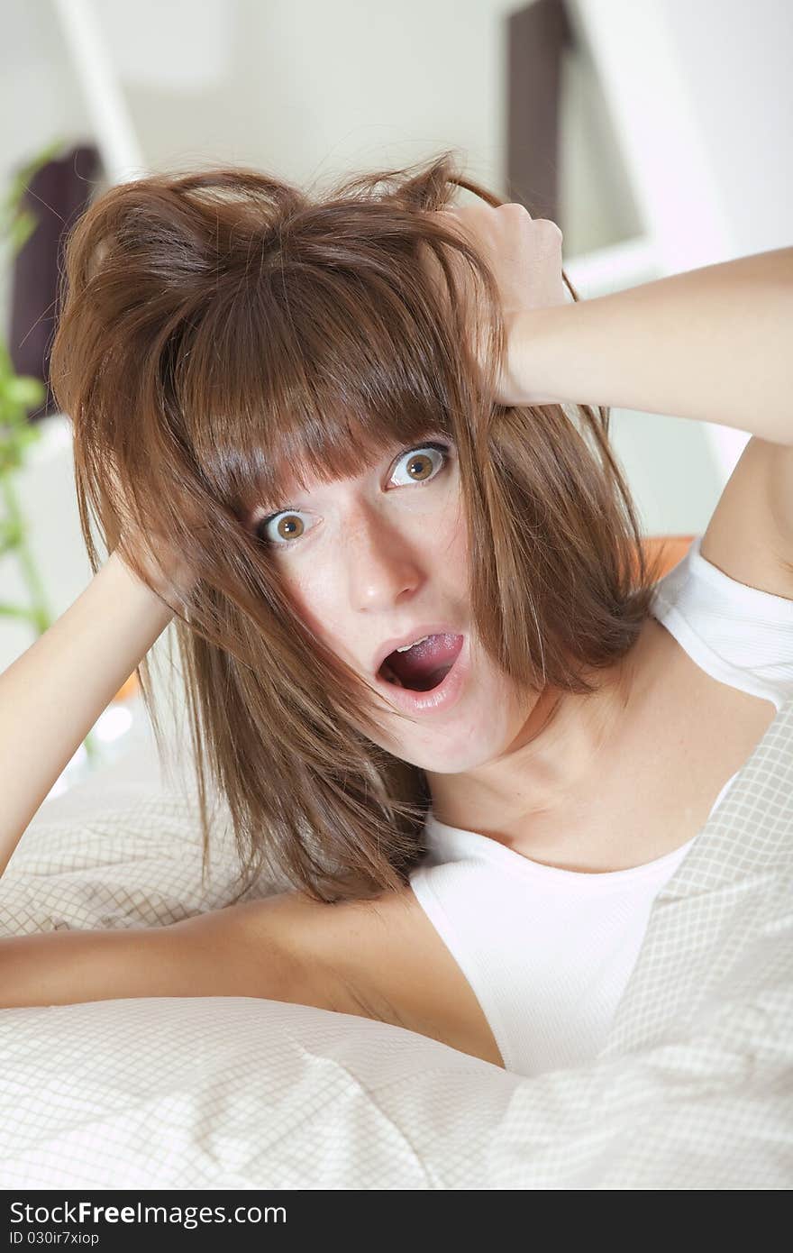 Bed clock alarm - surprised woman in bed holding her head with both hands