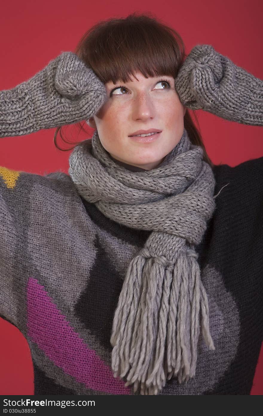 Casual woman in sweater and gloves over red background