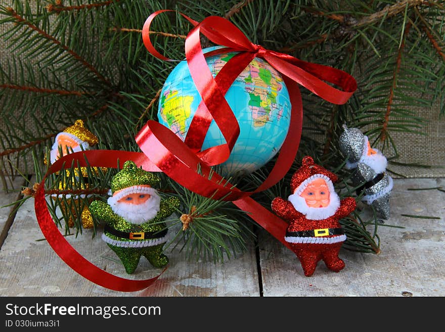 Globe with a gift ribbon and lots of Santa Clauses around. Globe with a gift ribbon and lots of Santa Clauses around