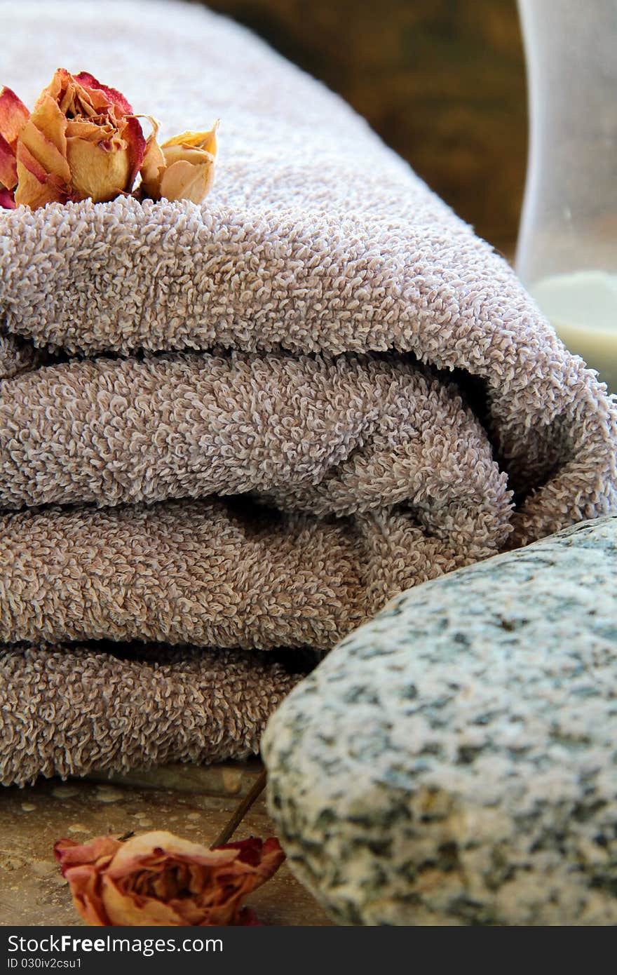 Gray towel with a rock and a candle and dry roses