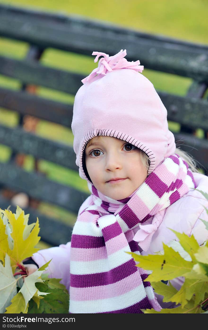 Pretty girl wooden sits on bench in autumn park