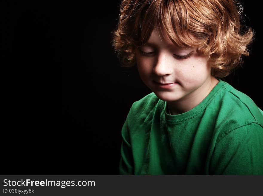 A cute young boy looking thoughtful/pensive on a black background. A cute young boy looking thoughtful/pensive on a black background.