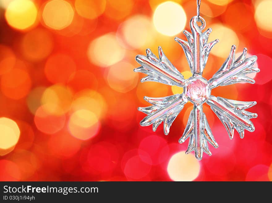 Glass snowflake against red blurred background