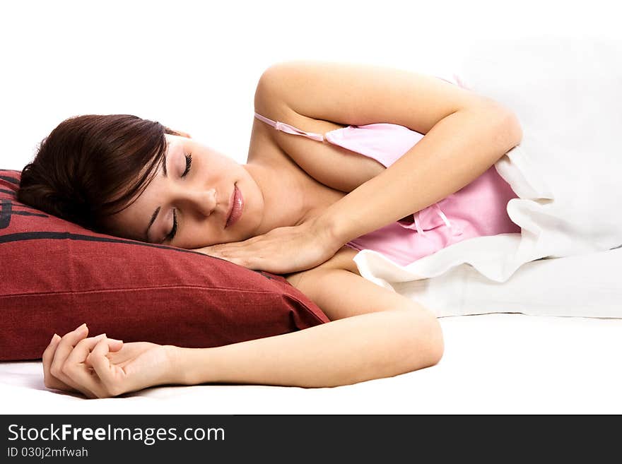 Portrait of a beautiful young woman sleeping on the white bed with red pillows. (isolated background)