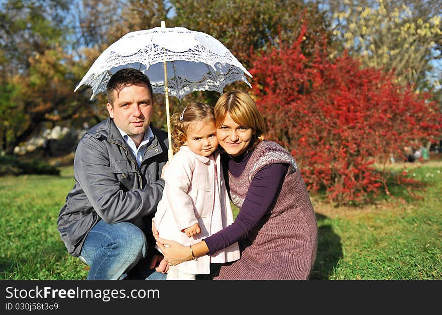 Happy family, mom and dad and their little girl under umbrella. Happy family, mom and dad and their little girl under umbrella