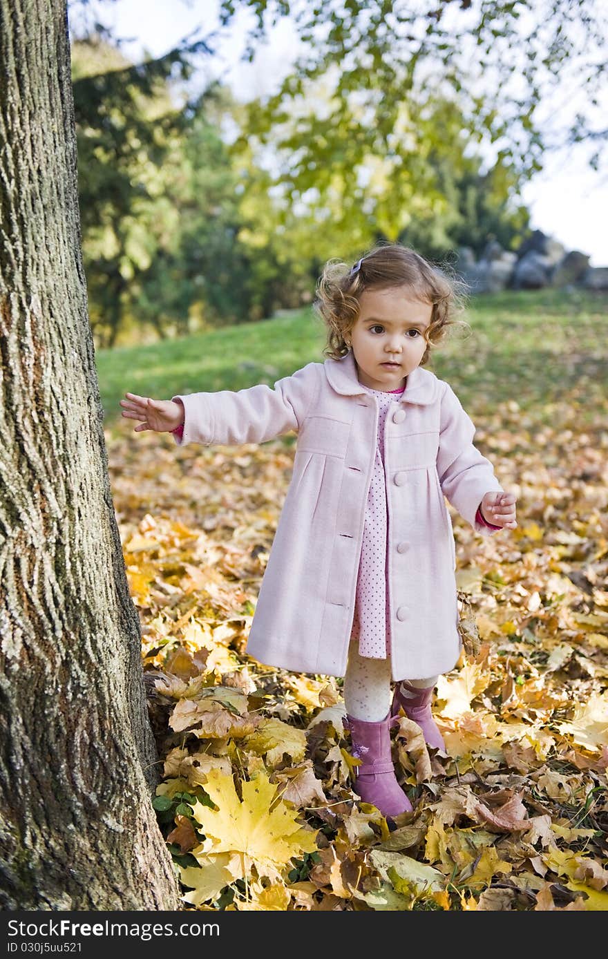 Little girl walking trough leaves in the park , in a autumn day