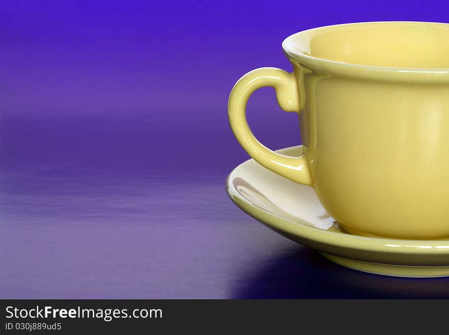 Closeup of empty coffee or tea yellow cup on blue background with copy space. Closeup of empty coffee or tea yellow cup on blue background with copy space