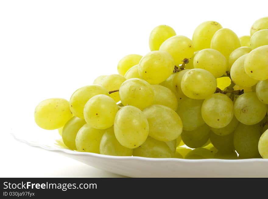 Grape bunch on the plate fragment isolated over white background (macro shot). Grape bunch on the plate fragment isolated over white background (macro shot)