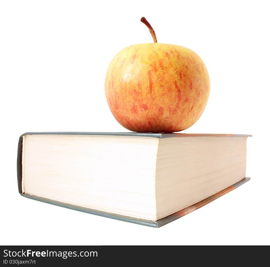 Yellow with red apple lies on corner of closed book. It is isolated on white background, without shadow.