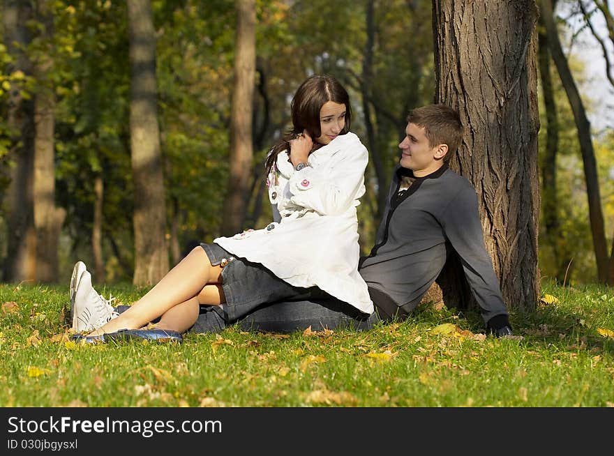 Young couple sitting in the autumn city park (defocused background). Young couple sitting in the autumn city park (defocused background)