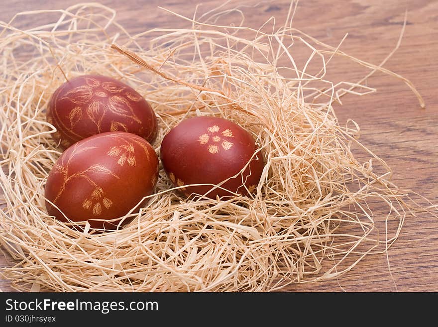 Hand painted red Easter eggs in the hay on a wooden table. Hand painted red Easter eggs in the hay on a wooden table.