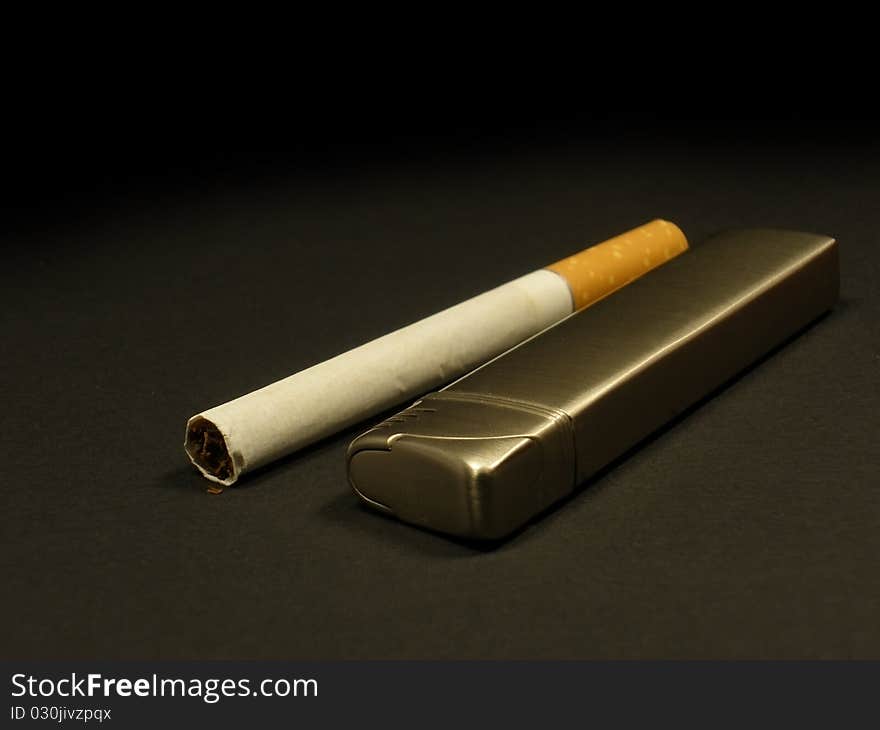 Cigarette and lighter on the dark grey background