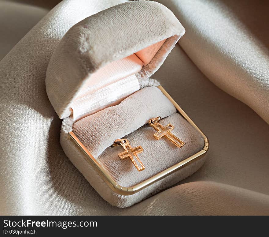 Two golden crosses in a box over beige background. Two golden crosses in a box over beige background.