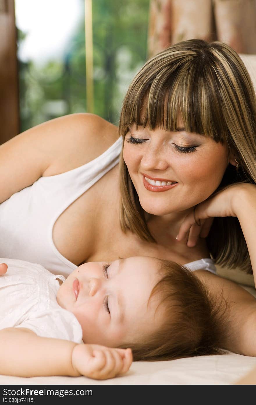 Lovely mother with her little daughter laying in the bed