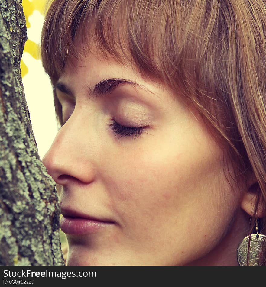 Girl at a tree with the closed eyes