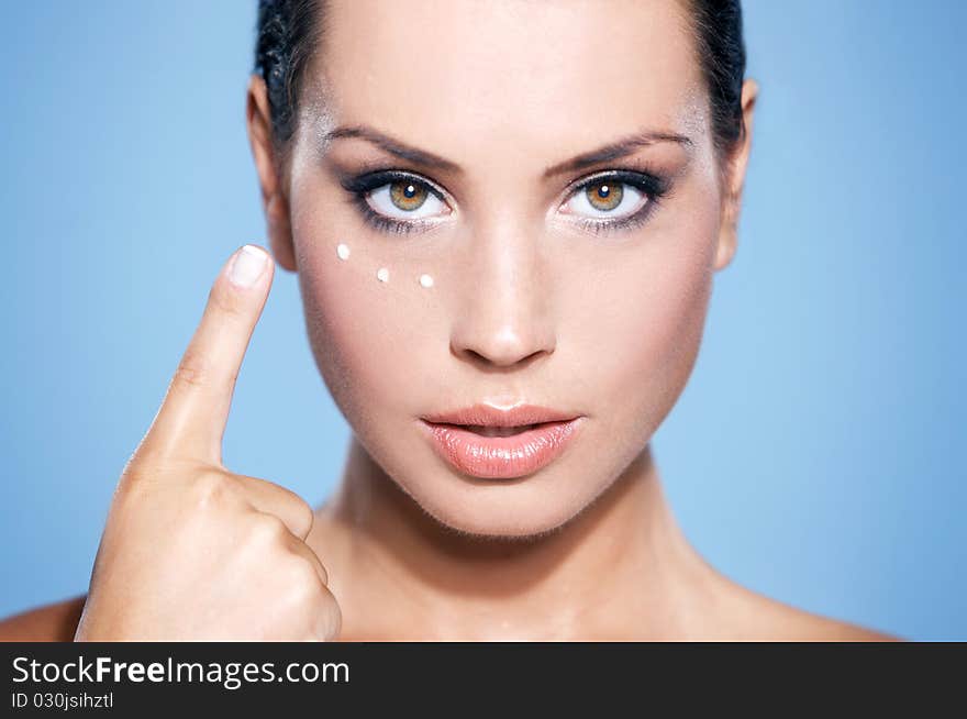 Portrait of beautiful woman, she has cream on her finger, isolated on blue. Portrait of beautiful woman, she has cream on her finger, isolated on blue