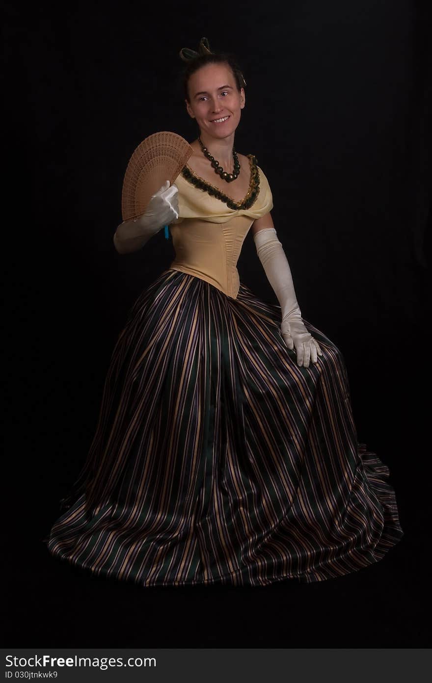 Sitting girl in nineteenth century dress isolated on black