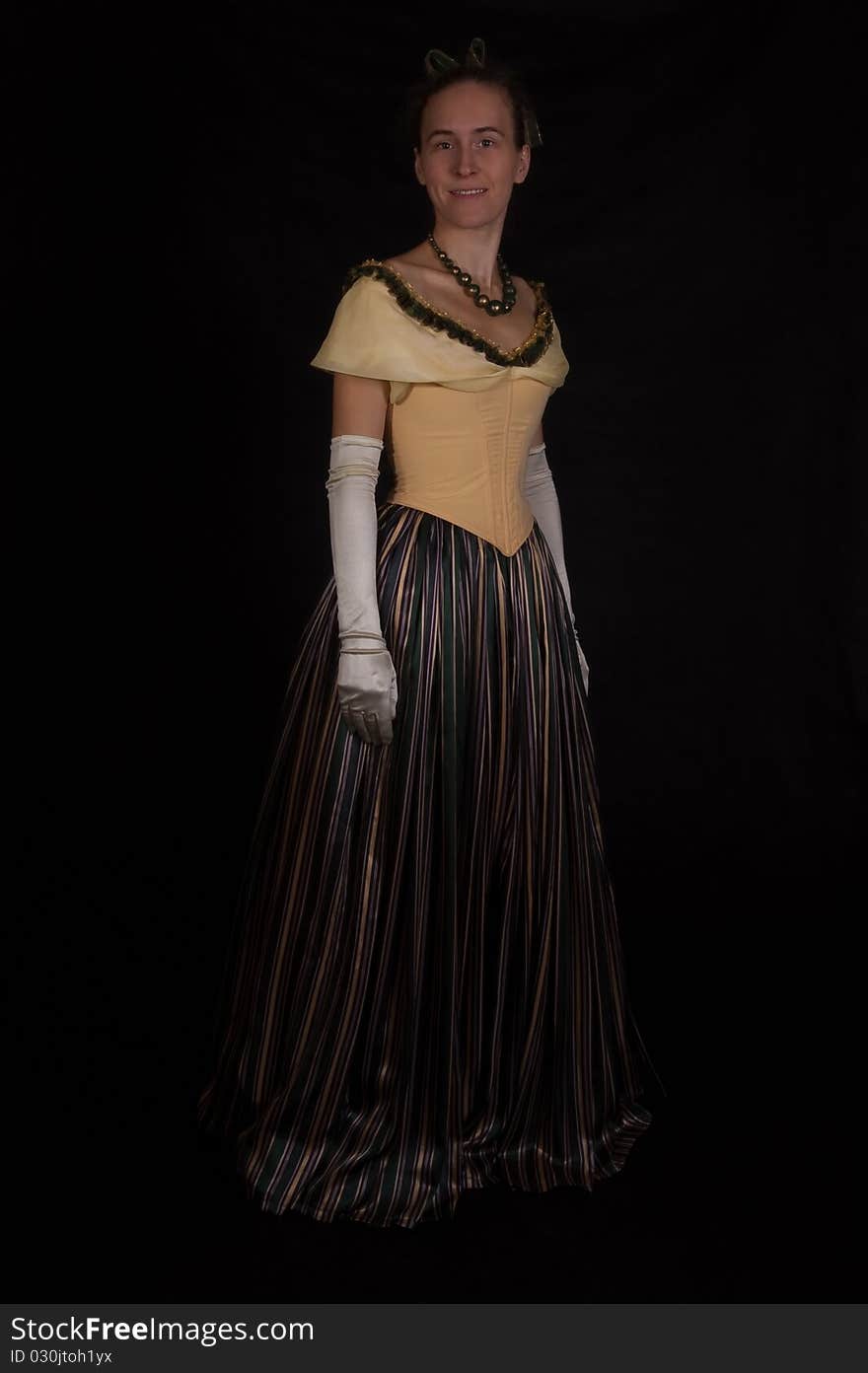 Standing girl in nineteenth century dress isolated on black