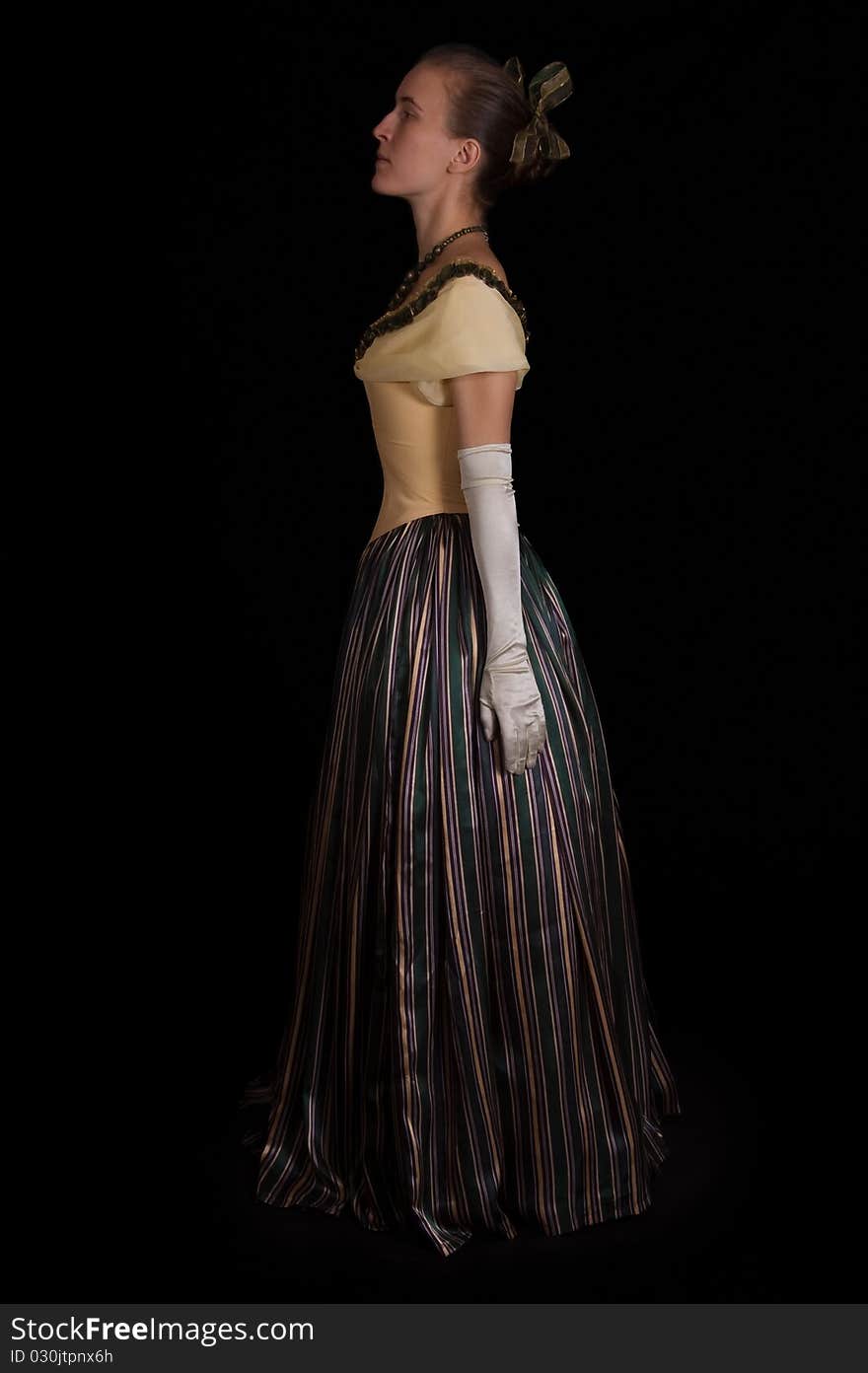 Standing girl in nineteenth century dress isolated on black