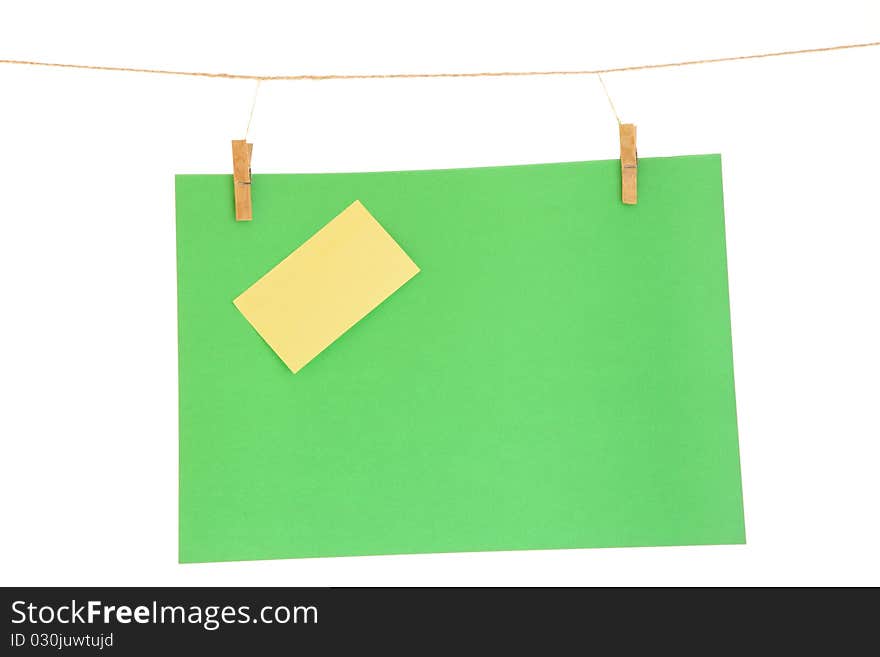 Green blank paper sheet on a clothes line. Isolated on white background. Green blank paper sheet on a clothes line. Isolated on white background.