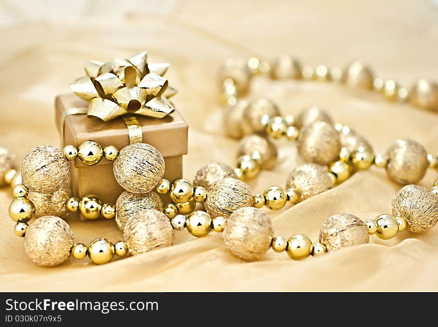 The gold background gold gift box with a string of Christmas ornamental ball. The gold background gold gift box with a string of Christmas ornamental ball.