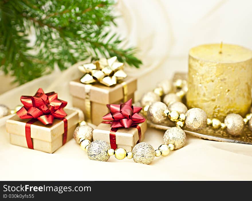 The gold background with a Christmas candle ball chains and gift boxes, a back background fir twig. The gold background with a Christmas candle ball chains and gift boxes, a back background fir twig.