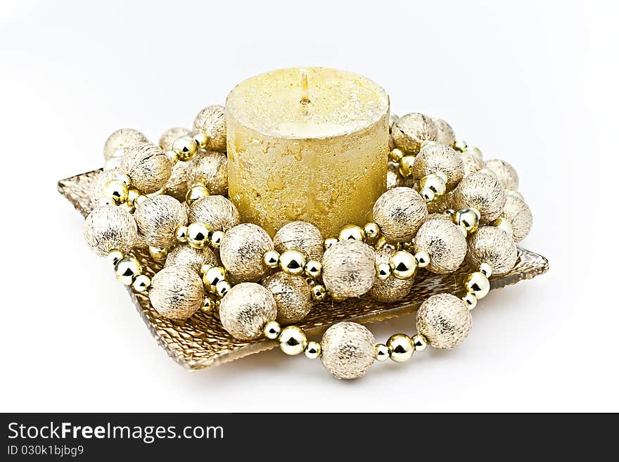 Isolated on white background gold candle in a glass dish with a decorative string of bombs. Isolated on white background gold candle in a glass dish with a decorative string of bombs.