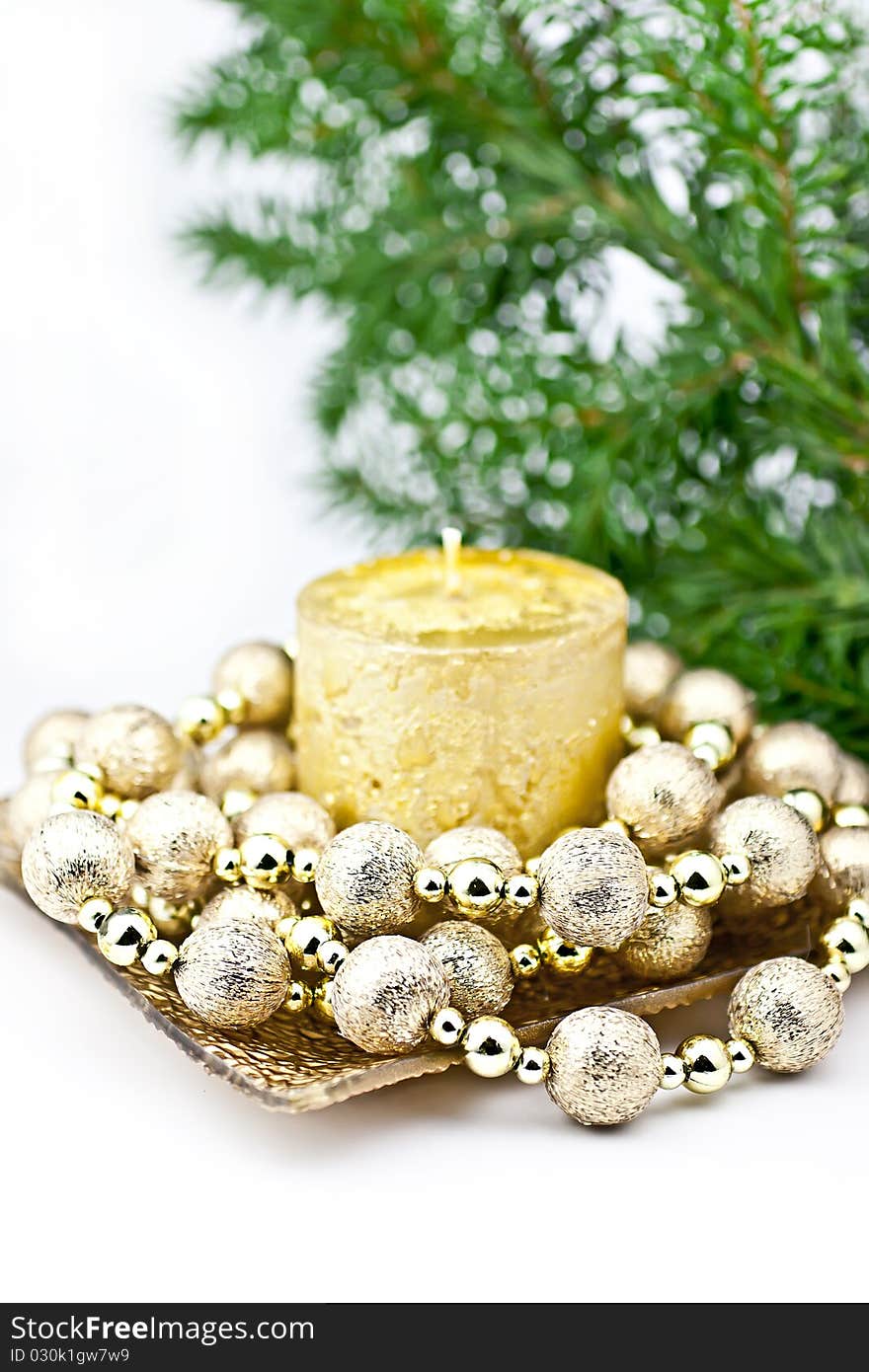 The white candle with a string of Christmas ball, a back background fir twig. The white candle with a string of Christmas ball, a back background fir twig.