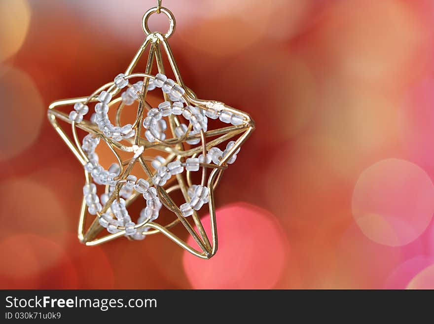 Star on branch of Christmas tree against red blurred background. Star on branch of Christmas tree against red blurred background