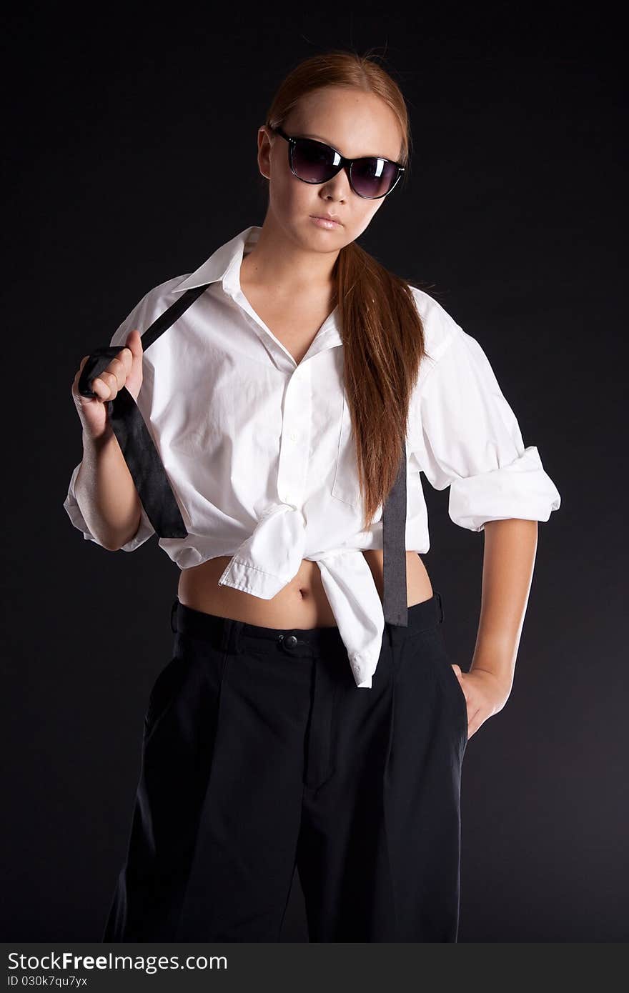 Serious girl in sunglasses on black background