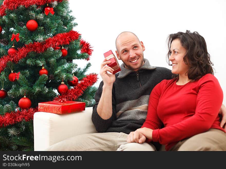 Young man near the Christmas tree wondering what is inside the gift. Young man near the Christmas tree wondering what is inside the gift