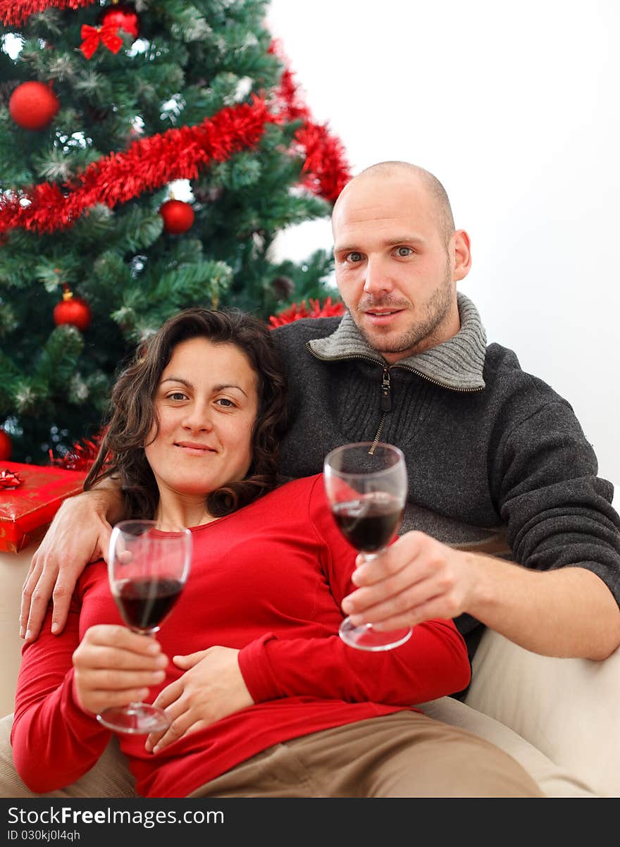 Young couple at sofa celebrating Christmas with a cup of wine. Young couple at sofa celebrating Christmas with a cup of wine