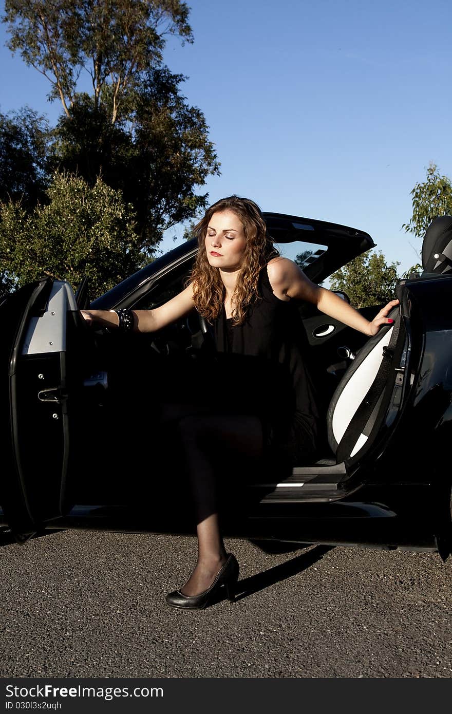 View of a beautiful woman exiting a sports car. View of a beautiful woman exiting a sports car.