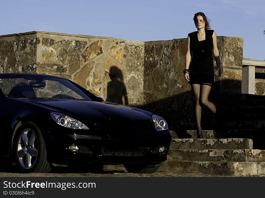 View of a beautiful woman next to sports car on a fashion pose. View of a beautiful woman next to sports car on a fashion pose.