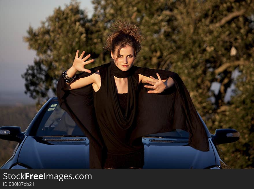 View of a beautiful woman next to sports car on a fashion pose. View of a beautiful woman next to sports car on a fashion pose.