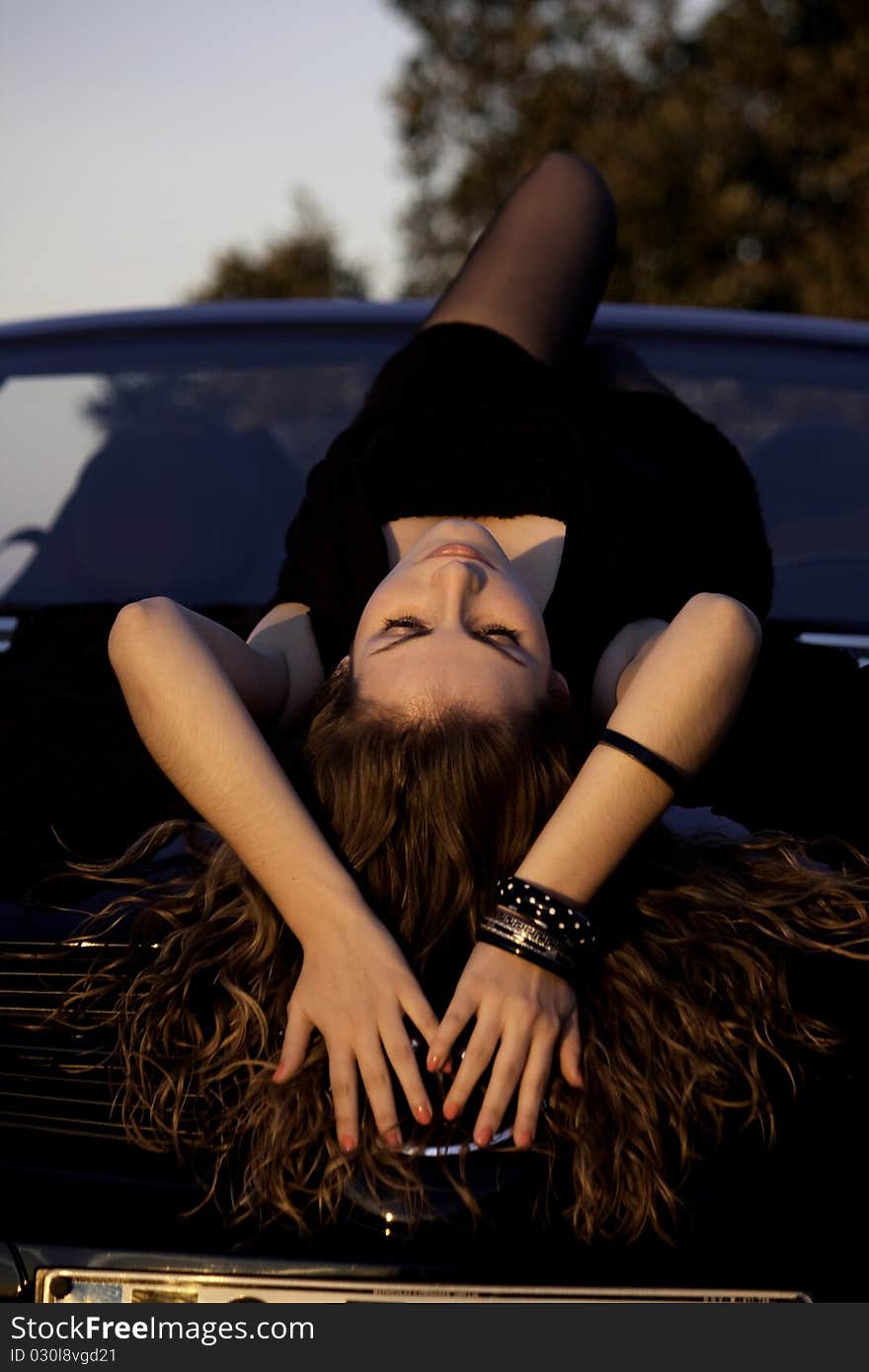 View of a beautiful woman on top of a sports car. View of a beautiful woman on top of a sports car.